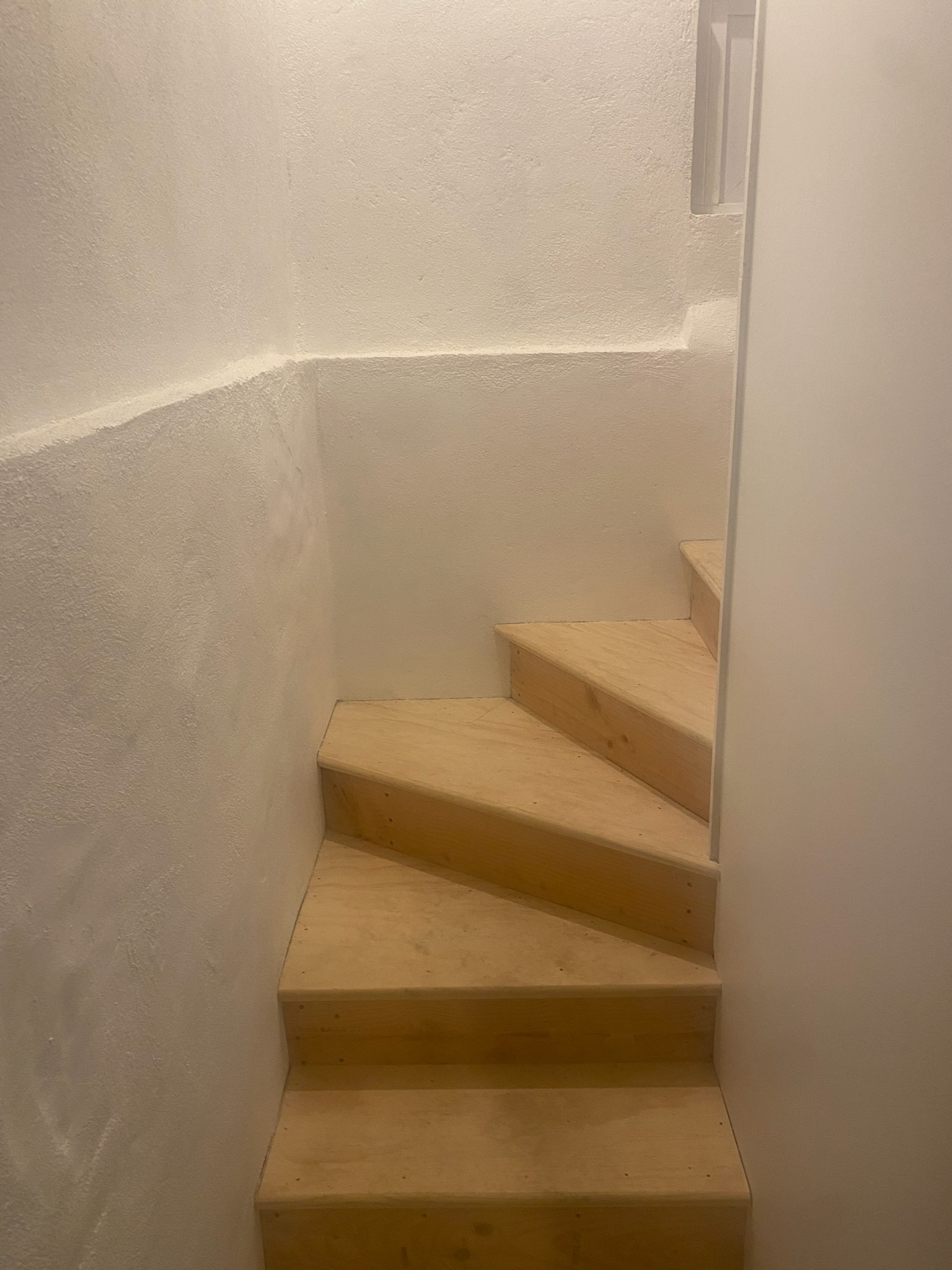 Finished wooden stairs in concrete basement with egress window