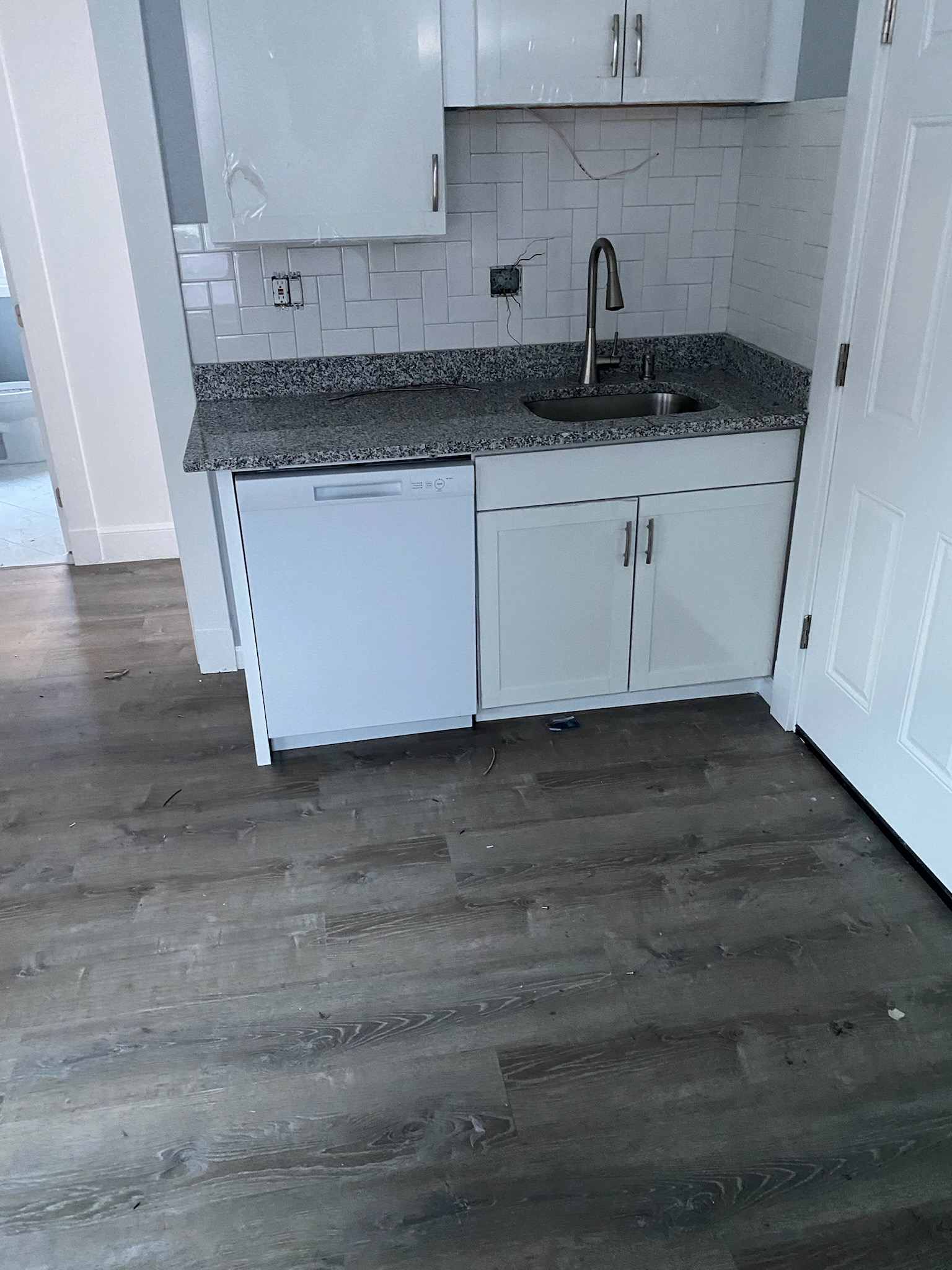 Kitchen after renovation — white shaker cabinets with granite